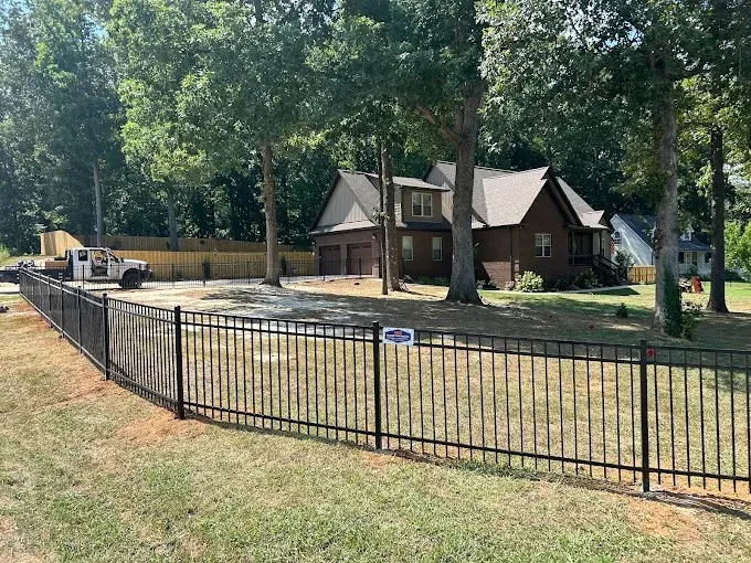 Black aluminum fence section and gate along a landscaped yard edge